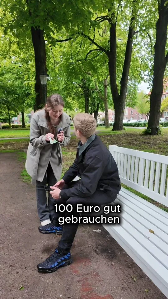The creator hands the prize to a man on a park bench